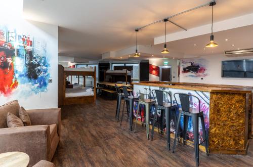 a living room with a bar with chairs and a couch at The Bling Hotel by UStay Aparthotels in Liverpool