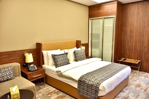 um quarto de hotel com uma cama e uma cadeira em Royal Vista Hotel em Ibri