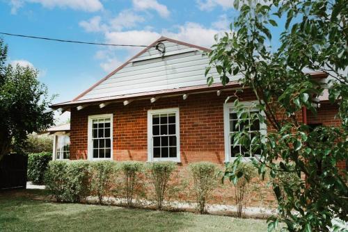 a red brick house with a fence in front of it at 'Mortimer Gardens' Country Charm in the Heart of Mudgee in Mudgee