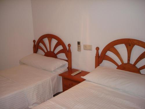 a bedroom with two beds and a wooden headboard at Pensión sol y playa in Carboneras