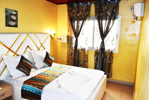 a bedroom with a bed and a window at Résidence Hotelière Borel Denver in Douala