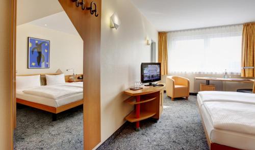 a hotel room with a bed and a desk with a computer at ABACUS Tierpark Hotel in Berlin