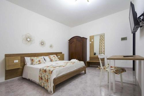 um quarto com uma cama, uma secretária e uma televisão em La Paranza Apartments Lampedusa em Lampedusa