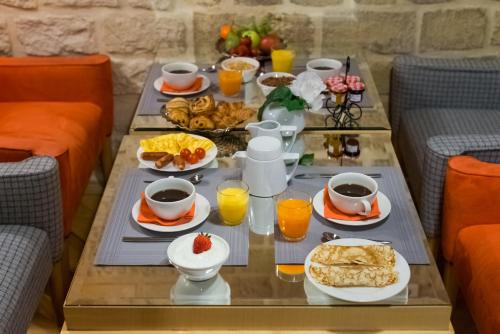 uma mesa de pequeno-almoço com alimentos de pequeno-almoço e sumo de laranja em Hotel Lorette - Astotel em Paris