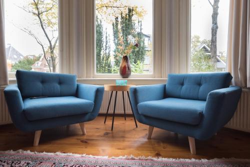 two blue chairs in a living room with a table at Boutique Appartement-Hotel Villa Juttershof in Bergen