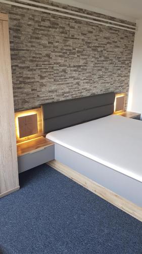 a bed in a room with a brick wall at Penzion ALICE in Zlín