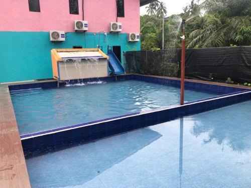a swimming pool in front of a building at Homestay/Bilik Teluk Gading in Kuala Rompin