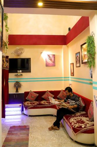 a man sitting on a couch in a living room at Hotel Mahishmati Palace in Maheshwar