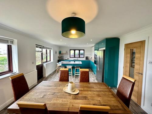 uma sala de jantar com uma mesa de madeira e cadeiras em Valley Lodge House - Porth Newquay em Newquay