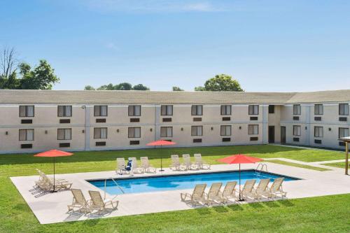 a large building with a pool and chairs and umbrellas at Ramada by Wyndham Allentown Bethlehem in Allentown