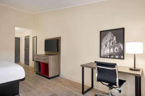 a hotel room with a bed and a desk and a tv at Ramada by Wyndham Allentown Bethlehem in Allentown
