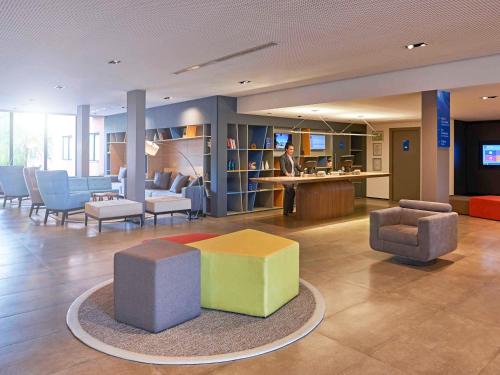 a lobby with a table and chairs and a person at Novotel Campo Grande in Campo Grande