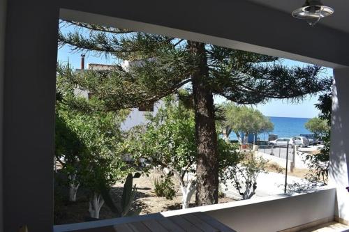 ein Fenster mit Blick auf einen Baum und das Meer in der Unterkunft Blackbeard's House - Kastri Crete in Kastrí