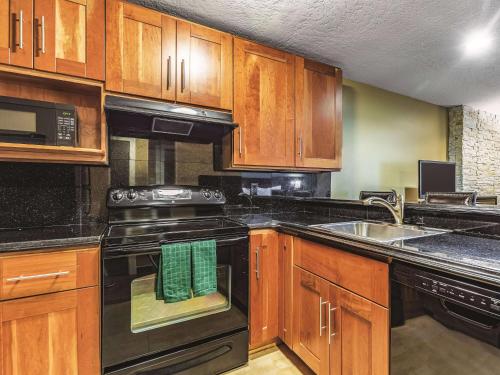 a kitchen with wooden cabinets and black appliances at La Quinta by Wyndham San Francisco Airport West Millbrae FREE AIRPORT SHUTTLE in Millbrae