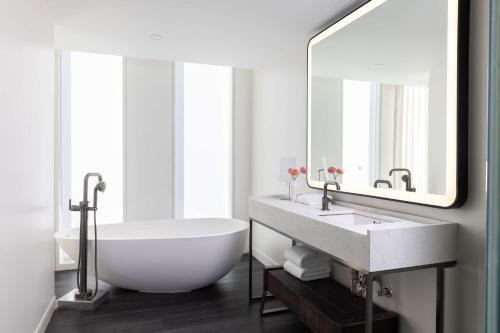 a bathroom with a tub and a sink and a mirror at Hyatt Centric Congress Avenue Austin in Austin