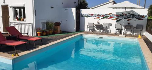 een zwembad met stoelen, een tafel en een parasol bij Casa Coloridos in Óbidos