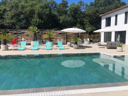 a swimming pool with blue chairs and an umbrella at Luxury Zen in Châteauneuf