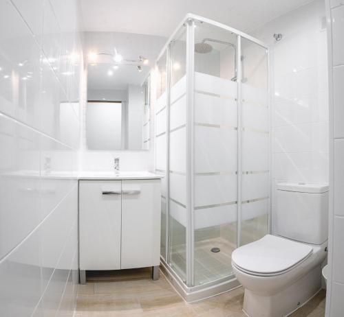 La salle de bains blanche est pourvue d'une douche et de toilettes. dans l'établissement Spondylus Apartment, à Empuriabrava