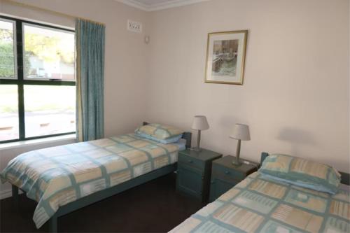 a bedroom with two beds and a window at Constantia Cottage in Cape Town