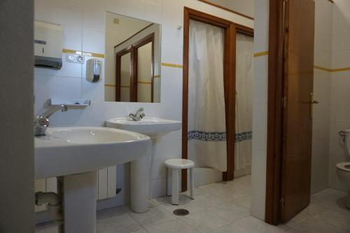 a bathroom with two sinks and a shower and a toilet at Albergue de Sos del Rey Católico in Sos del Rey Católico
