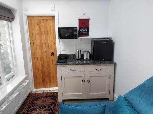 a room with a kitchen with a counter with a microwave at Peaceful Self-contained room near Looe in Looe