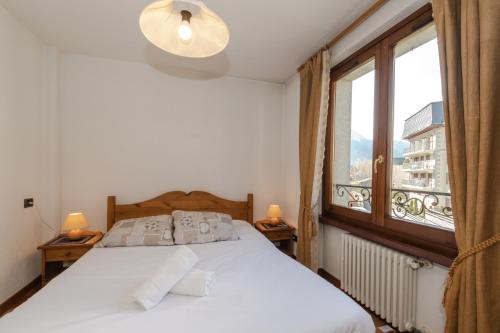 um quarto com uma cama e uma grande janela em Résidence Alpes 2 em Chamonix-Mont-Blanc