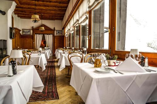 een rij tafels in een restaurant met witte tafelkleden bij Hotel Fex in Sils Maria