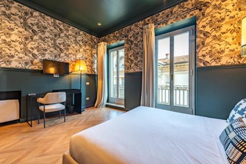 a bedroom with a bed and a desk and window at DH Rooms Spiga in Milan
