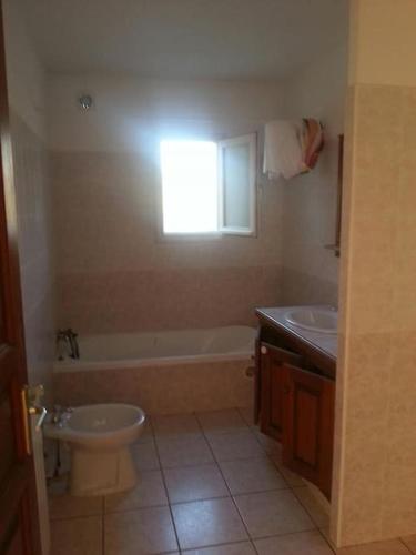 une salle de bain avec toilettes, baignoire et lavabo dans l'établissement bas de villa de 90m² entre mer (2km) et montagne, à Talasani