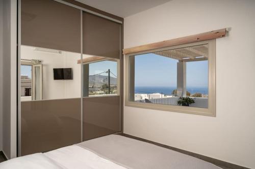 a bedroom with a bed and a large window at In the heart of Fira & free pool - Nychteri suite in Fira