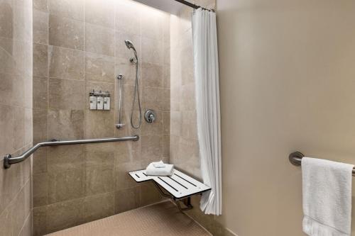 y baño con ducha y asiento de ducha. en Magnolia Hotel Houston, a Tribute Portfolio Hotel en Houston