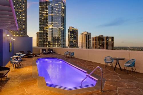 a pool on the rooftop of a building with a city skyline at Magnolia Hotel Houston, a Tribute Portfolio Hotel in Houston