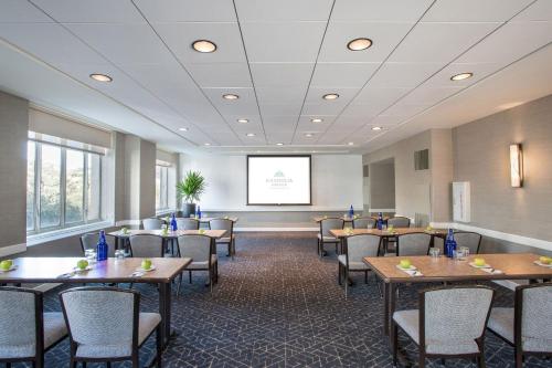 a conference room with tables and chairs and a screen at Magnolia Hotel Houston, a Tribute Portfolio Hotel in Houston