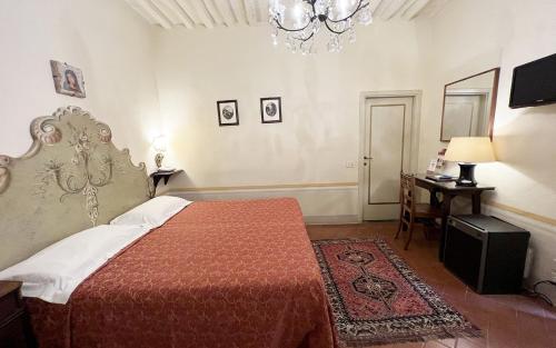a bedroom with a bed and a table and a chandelier at B&B Piccolo Hotel in Cortona