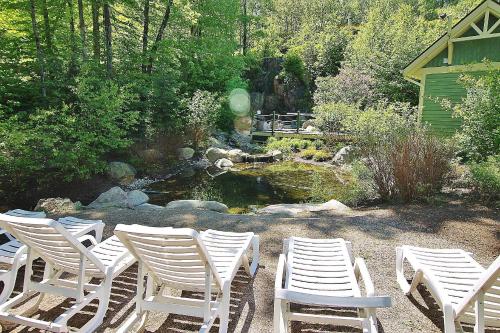 a group of white chairs sitting in front of a pond at Tremblant Les Eaux by Rendez-Vous Mont-Tremblant in Mont-Tremblant