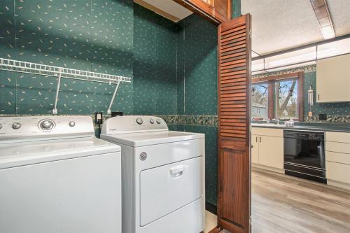 a kitchen with a washing machine and a green wall at The Sugar Maple Home in South Haven