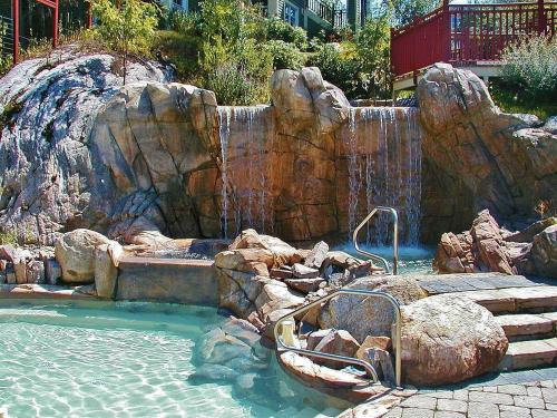 a swimming pool with a waterfall and a rock wall at Tremblant Les Eaux by Rendez-Vous Mont-Tremblant in Mont-Tremblant