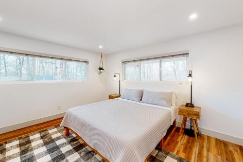 a white bedroom with a bed and two windows at Donington Delight in Bella Vista