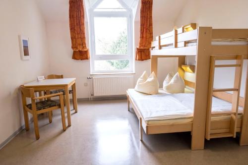 a bedroom with two bunk beds and a table and a desk at Jugendherberge Kappeln in Kappeln