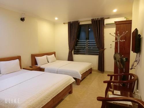 Una habitación de hotel con dos camas y un televisor. en Guesthouse Anh Khang, en Ha Long