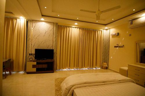 a bedroom with a large bed and a television at Estrahet Al Haitham in Al Qal‘ah