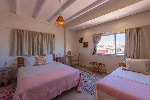 a bedroom with two beds and a window at Kite House Dakhla in Dakhla