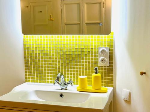 ein Bad mit einem Waschbecken, einem Spiegel und gelben Fliesen in der Unterkunft Le Yellow - Hôtel Particulier XIXème in Montpellier