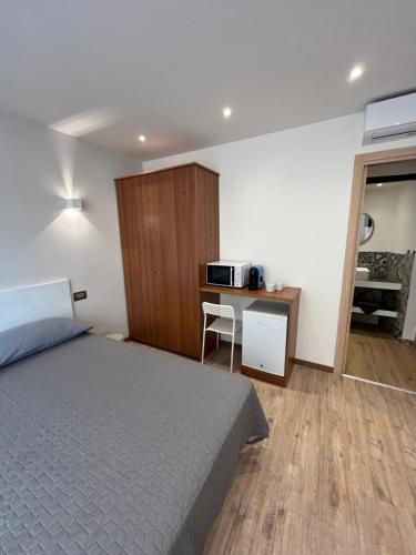 1 dormitorio con 1 cama y escritorio con microondas en Wowies room, en Pettenasco