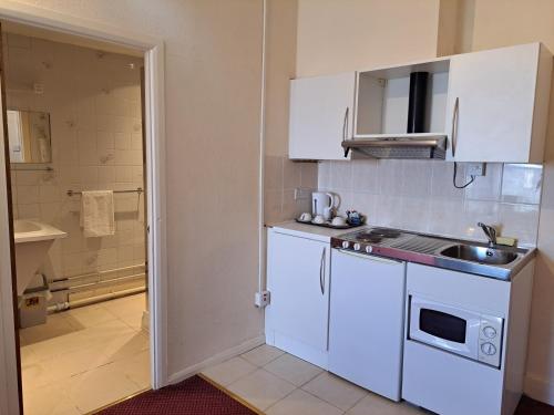 a small kitchen with white cabinets and a sink at Diamond House in Rugby