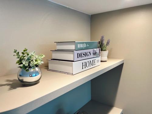 a shelf with books and a vase of flowers on it at Praia da Costa, SUNRISE STAY in Vila Velha