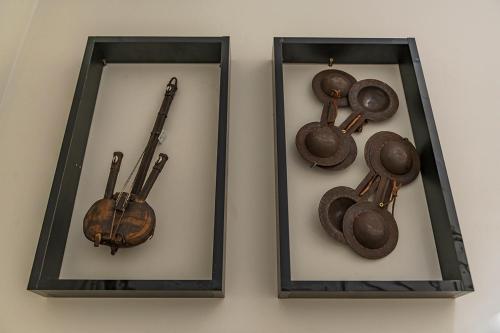two framed mirrors with a violin and pans on a wall at Kite House Dakhla in Dakhla