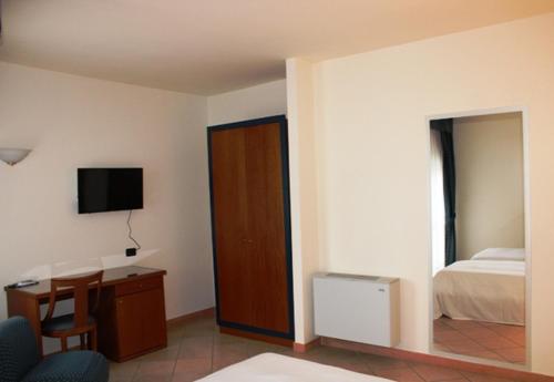 a bedroom with a bed and a desk and a television at DOMUS Grand Hotel in Rende
