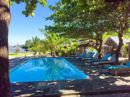 a swimming pool with lounge chairs and trees at La Case Du Pecheur in Grand Sable