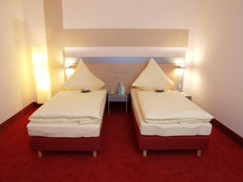 2 letti in una camera con tappeto rosso di Gästehaus Catherine a Zierenberg